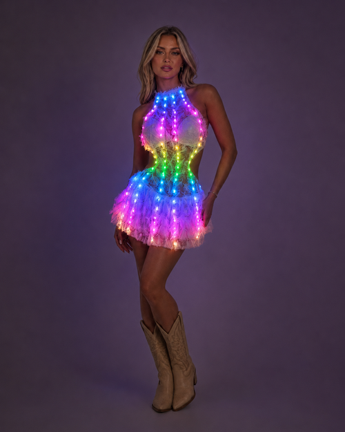 Model wearing the Halo LED Feather Mini Dress glowing in rainbow colours with cowboy boots