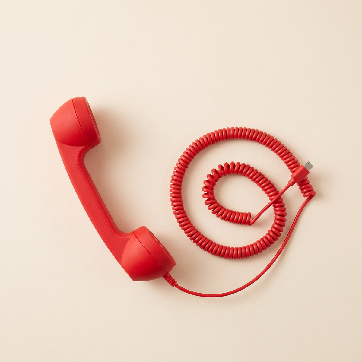 Talkie handset in Cherry with the coiled cord laid out in a spiral.